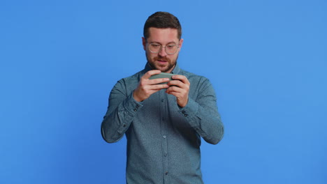 happy man playing racing drive simulator shooter video games on smartphone celebrate victory win