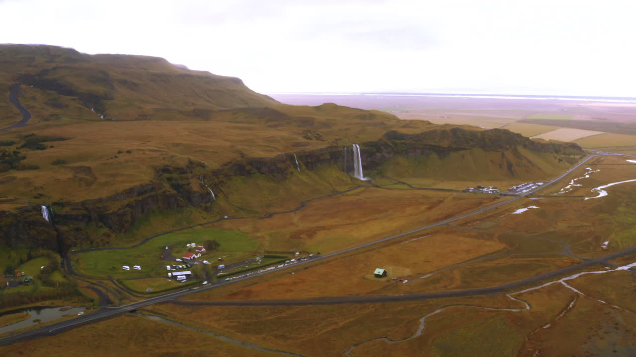 아이슬란드의 넓은 산 폭포 풍경, 아름다운 초록 평야와 폭포 근처의 작은 마을