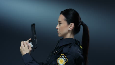 portrait shot of the young attractive policewoman turning to the camera and pointing a gun at the camera