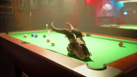 a skull with horns sits on a pool table in a dark bar