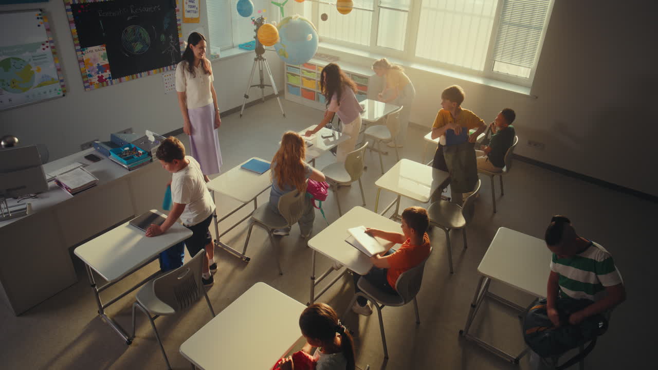 Elementary School Students Entering Classroom Unpacking Backpacks with School Supplies