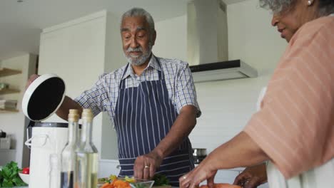 Happy-african-american-senior-couple-cooking-and-talking-together