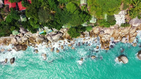 Hermoso-Día-Soleado-En-La-Costa-Rocosa-De-Tailandia-Con-Coloridas-Casas,-Palmeras-Y-Olas-Que-Se-Lavan-En-Las-Rocas