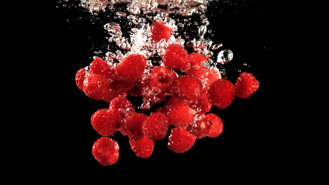 Red Raspberries Falling into Water in Slow Motion