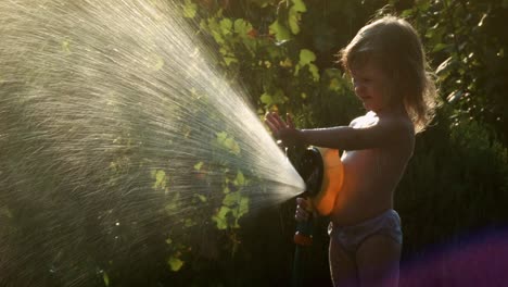 little girl playing with a water hose in the garden