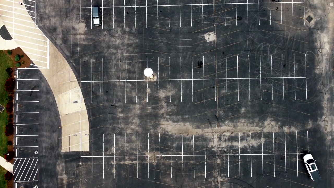 An ascending aerial view of a vacant and empty parking lot