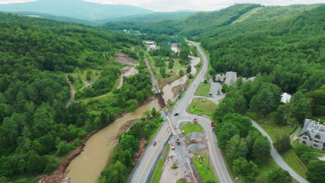 Überfluteter-Fluss-Und-Ufererosion:-Weitblick-Mit-Vorbeifahrenden-Autos-Auf-Der-Angrenzenden-Straße,-Vermont,-USA