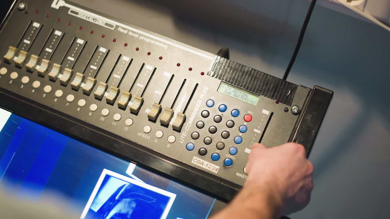 Close-up shot of hand pressing control button on video mixing console. Professional studio equipment in use, user adjusting settings on multimedia equipment in high-tech production environment