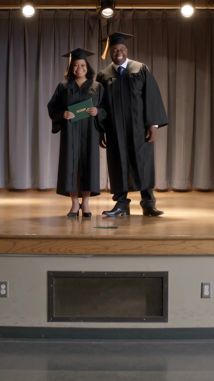 Vertical video: Cam panning grads in caps,gowns, man moving tassel posing on stage with green cover