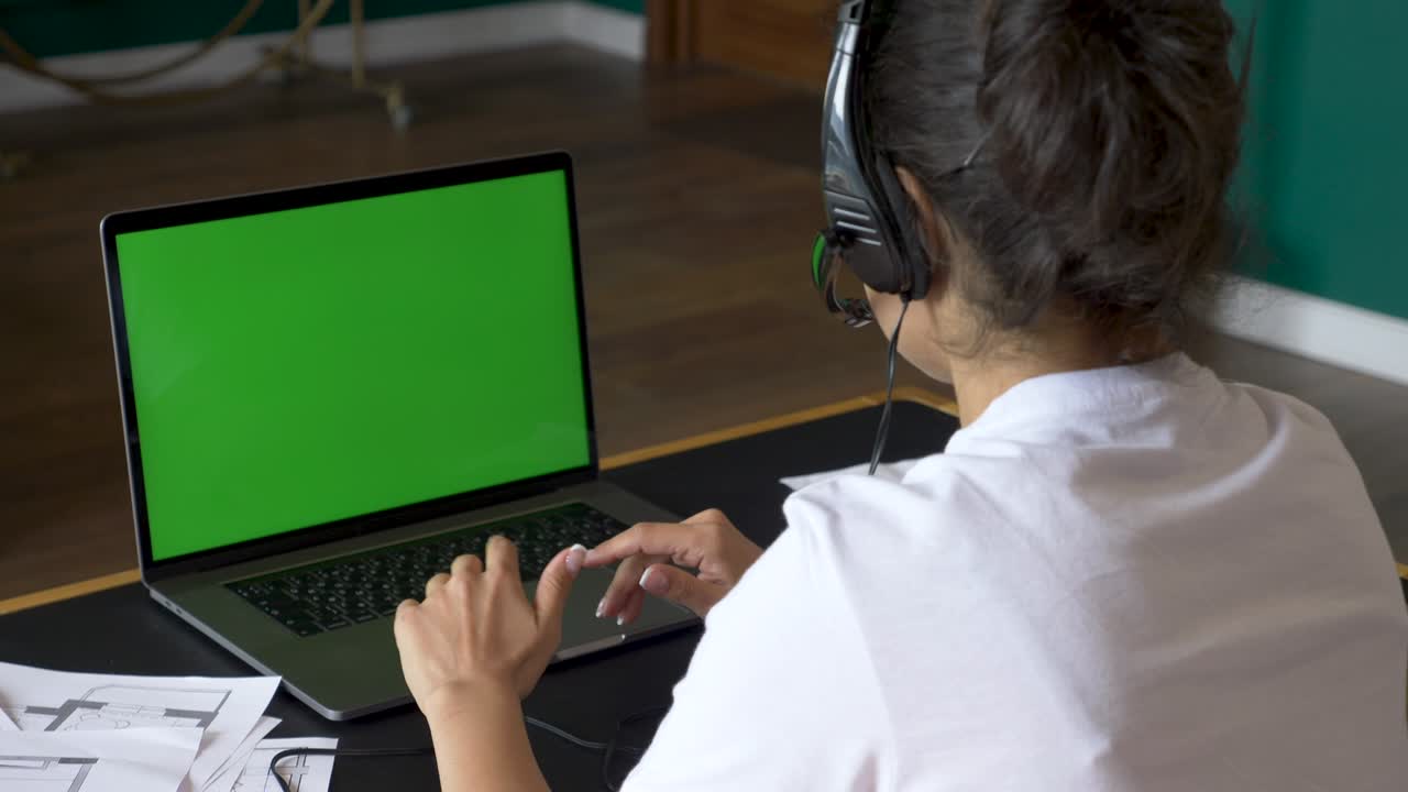 primer plano de una joven india que se comunica con un cliente usando una computadora portátil con una pantalla verde trabajando en una conferencia en línea, entrenando con personas, usando una ordenador. habitación brillante en la silla de la casa
