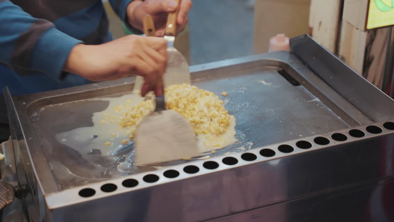 Taiwanese street food vendor grills cheesy corn to perfection, blending creamy toppings with smoky flavors in a bustling night market setting