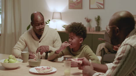 black men and boy eating dinner at home