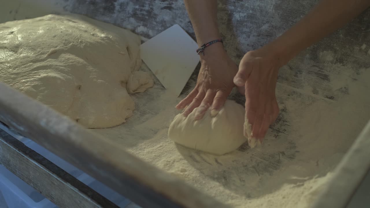 close up, women baker is preparing some bread loaf, kneading dough and placing it to rest in a osier basket cover by linen blanket