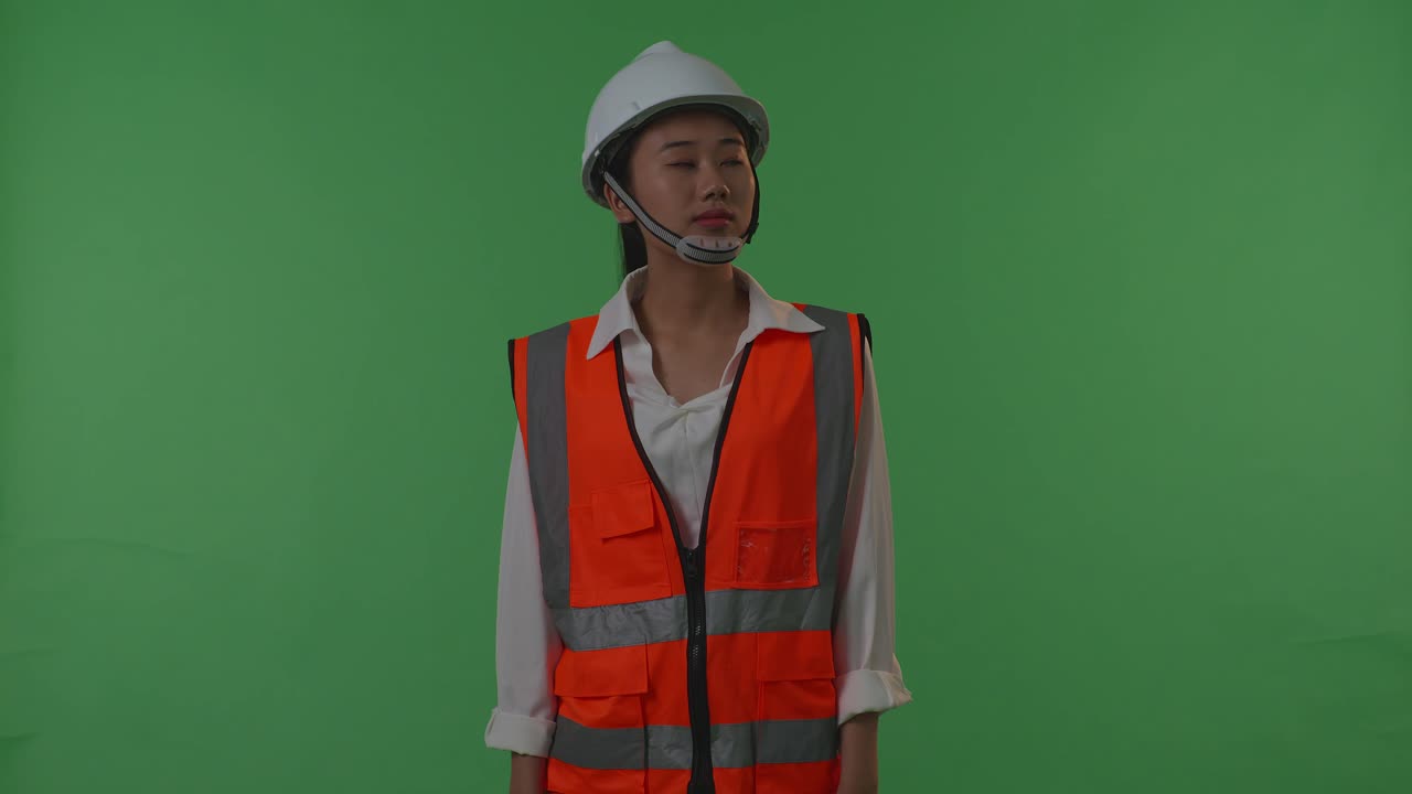 mujer en uniforme de trabajador de la construcción mirando hacia arriba en la pantalla verde
