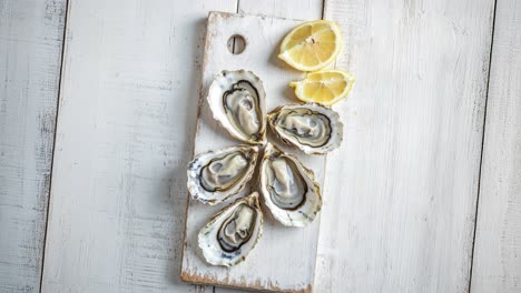 fresh oysters on rustic cutting board with lemon wedges