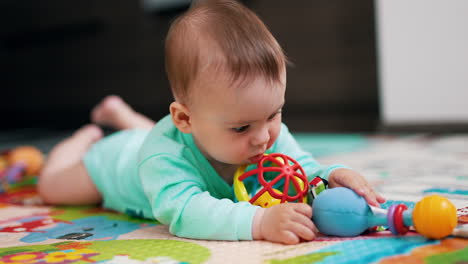 healthy active little toddler looking attentively on his toys. cheerful baby claps his hand over the floor. blurred backdrop.