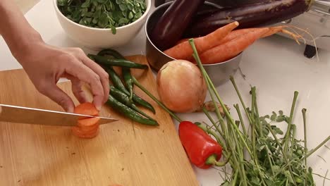 Overhead view of woman&#039;s hand slicing carrots into strips while preparing ingredients for cooking, candid moment of peaceful domestic home life