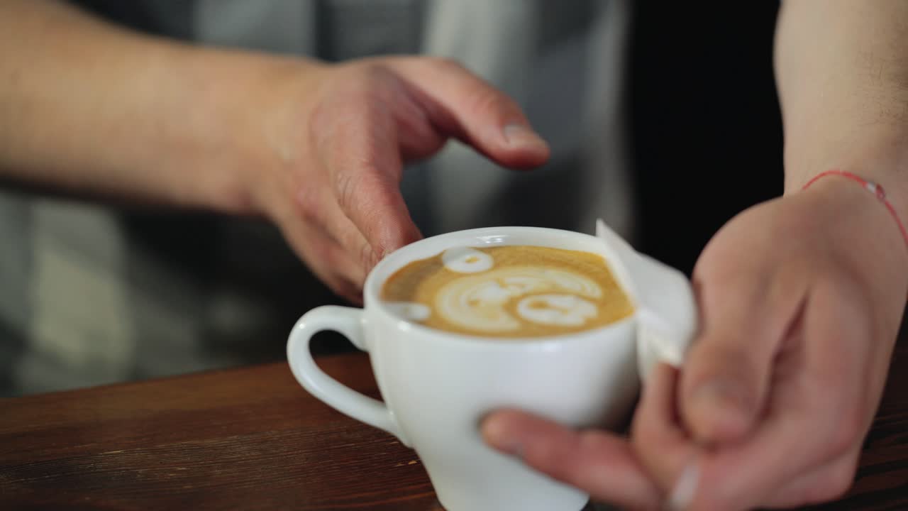 Professional Barista works in a coffee shop close-up, draws a pattern on a cappuccino Cup