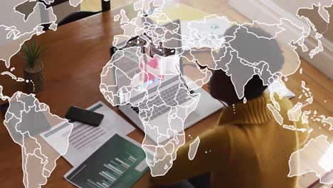 animation of world map over african american woman having a video call on laptop at home
