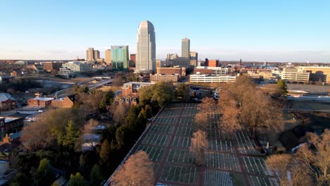 aerial-pushing-over-bald-cypress-trees-on-god's-acre-ground-pushing-toward-winston-salem-nc,-north-carolina-skyline