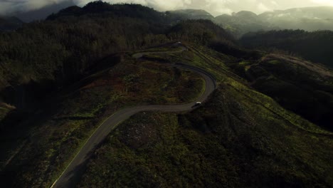 Coche-Conduciendo-Por-Una-Pintoresca-Carretera-Con-Curvas-Sobre-Las-Nubes-Al-Atardecer,-Madeira-4k