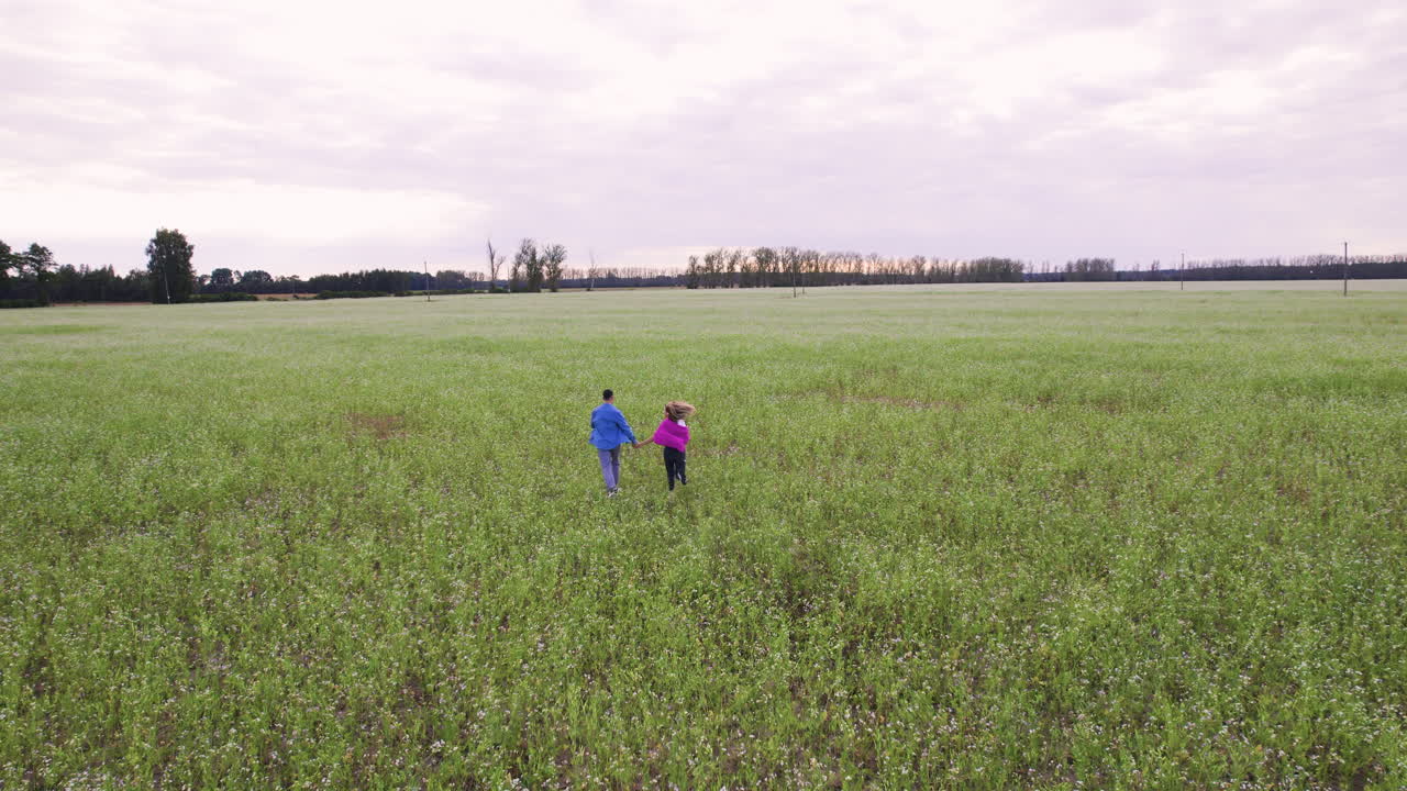 una pareja joven tomándose de la mano en un campo.