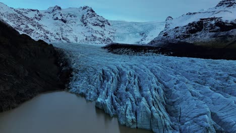 vista aérea del glaciar svinafellsjokull con profundas grietas en islandia rodeada de montañas nevadas