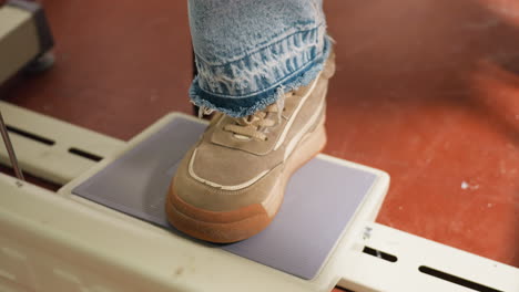 canvas shoe on pedal tailor on sewing machine, stepping with controlled force, ensuring stable posture, maintaining accuracy, demonstrating efficiency, focusing on skillful garment production