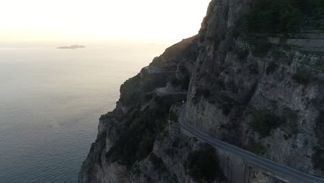a car is driving on the beautiful amalfi coast at sunset while a drone is following it