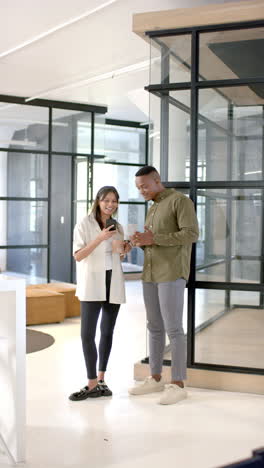 vertical video: discussing work, colleagues looking at smartphone in modern office setting