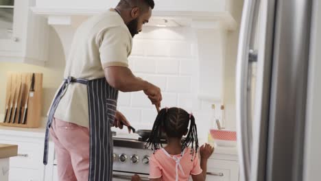 Happy-african-american-father-and-daughter-frying-pancakes-in-kitchen,-slow-motion