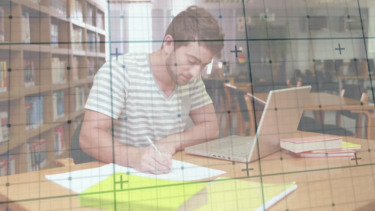 Studente universitario che scrive su dei fogli, poi sposta lo sguardo sul laptop e digita per motivi di studio.