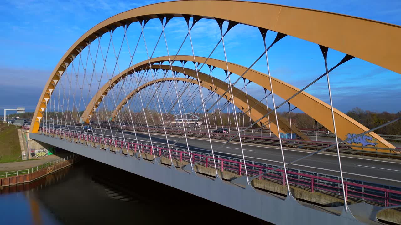 Arch bridge carrying a highway over a canal with cars moving, showcasing infrastructure and transportation in germany. Brilliant aerial view ascending raise up drone