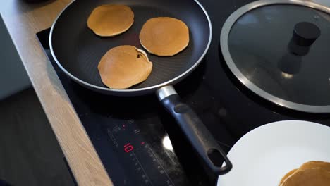 the close-up shot of frying pancakes in the pan at home kitchen, process of making breakfast, slider shot