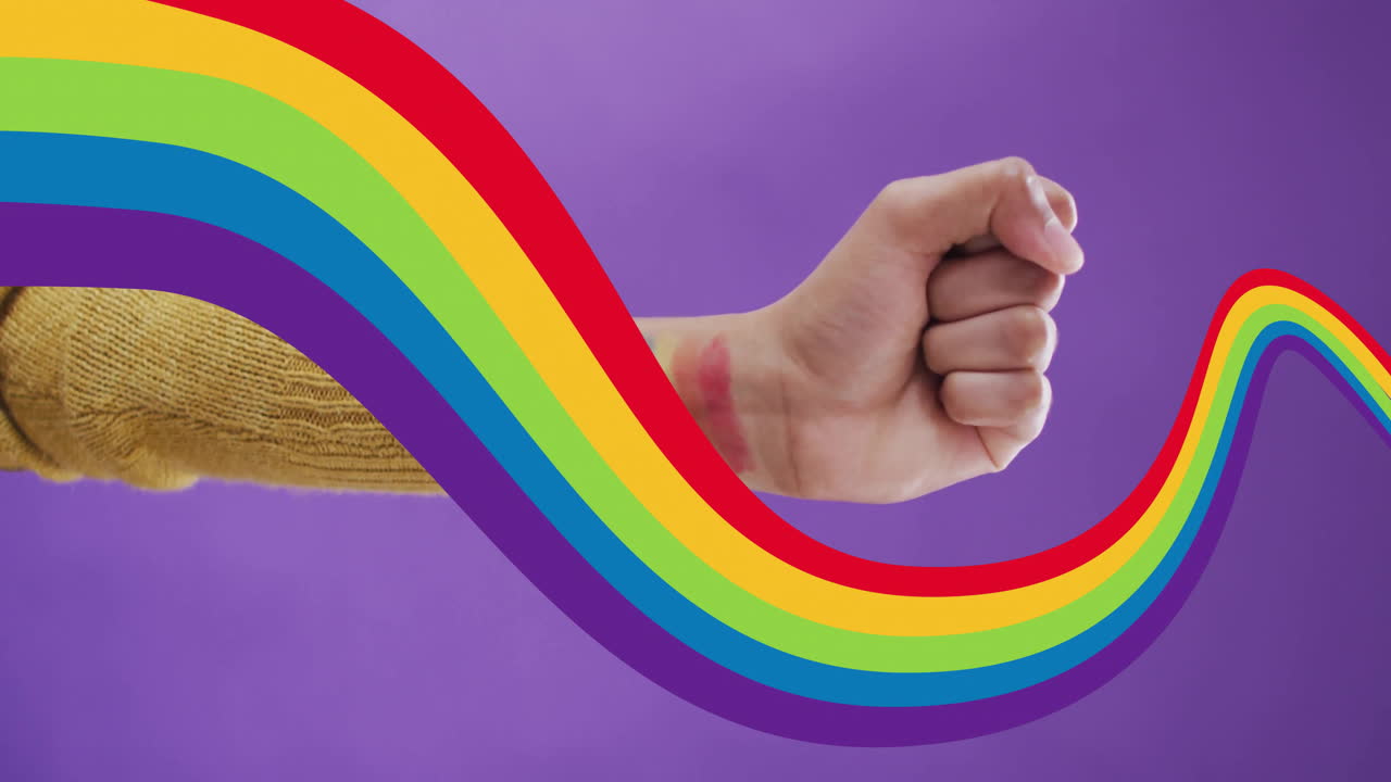 puño levantado con animación de arco iris en fondo púrpura, simbolizando el orgullo