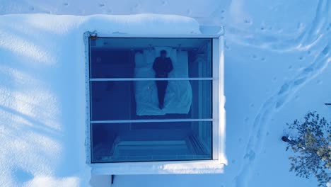 a bird'seyeview zooms out from a man resting in bed at the northern lights ranch revealing the snowy landscape that surrounds his lodgings