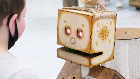 a little boy is talking to a wooden robot a little boy is talking to a wooden robot wooden retro robot