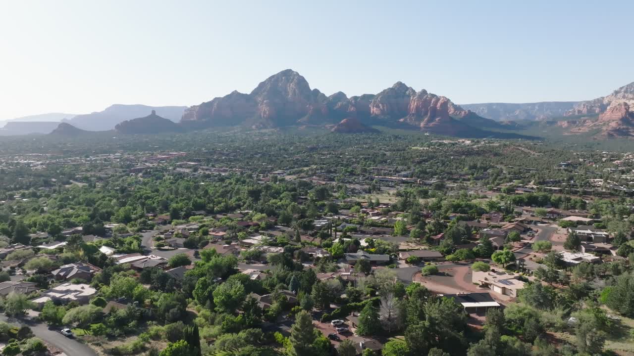 sedona con barrios verdes y montañas de roca roja bajo un cielo despejado, vista aérea