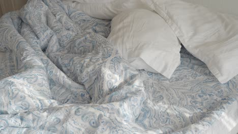 unmade bed with blue and white bedding