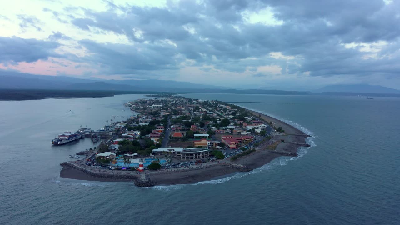 nubes rosadas el cielo al atardecer sobre la pequeña ciudad de puntarenas en costa rica, sobrevuelo de drones de 4k