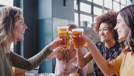 four young female friends meeting for drinks and food making a toast in restaurant