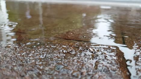 Gotas-De-Agua-Cayendo-En-Un-Charco-De-Agua-Sobre-Ladrillos-De-Arenisca,-Imágenes-En-Cámara-Lenta