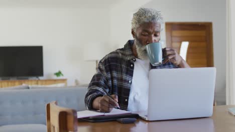 senior man drinking coffee while taking notes