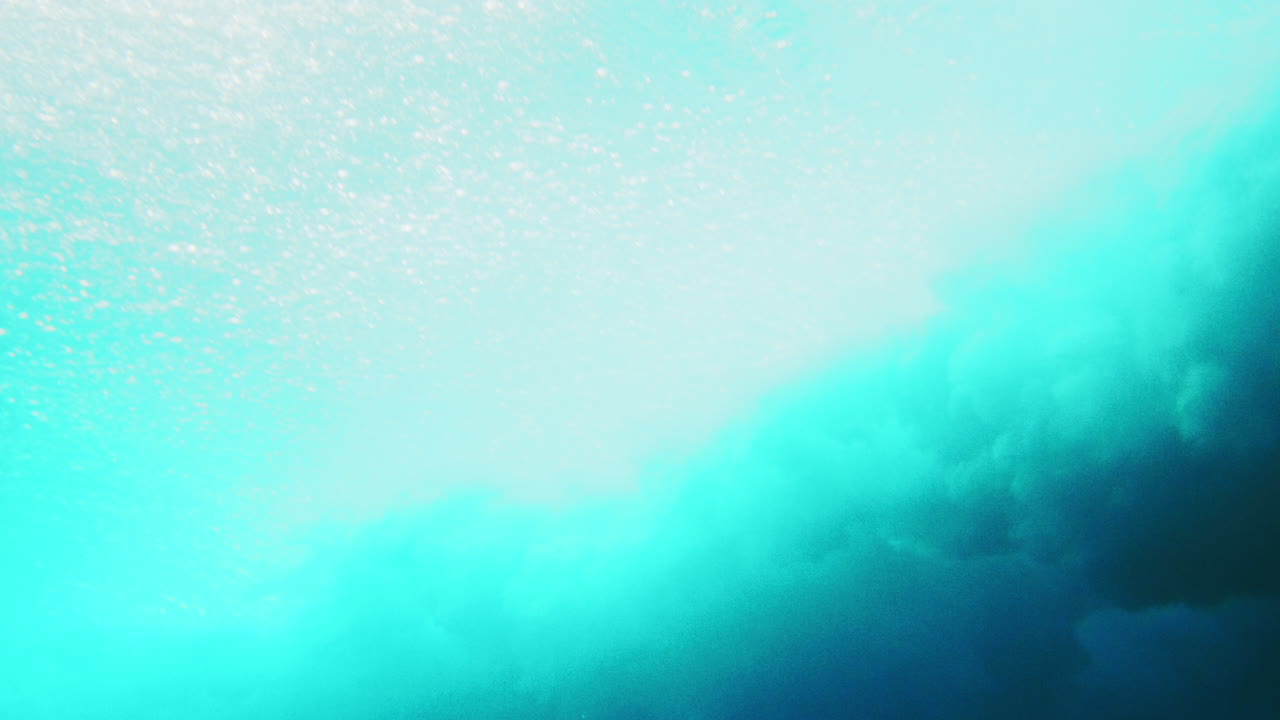 spray oceánico se lanza hacia adelante a través de la superficie como se ve desde debajo del agua