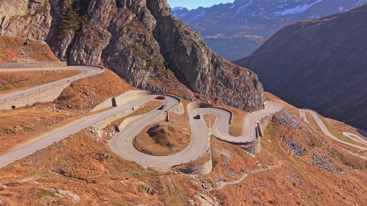 Aerial shot of sports car driving iconic curves of Tremola Road, Alps