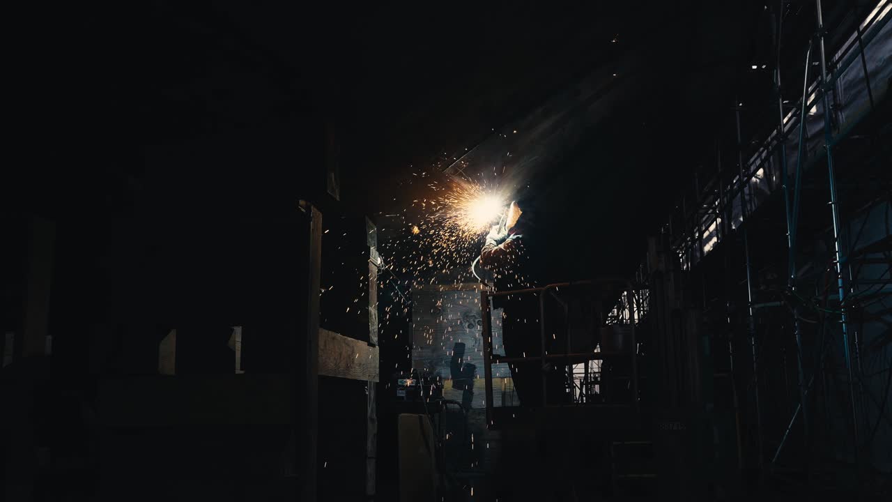 스파크가 여기저기 날아다니는 오래된 배에서 금속을 함께 용접하는 사람의 넓은