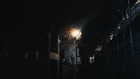 wide shot of a man welding metal together on an old ship with sparks flying everywhere