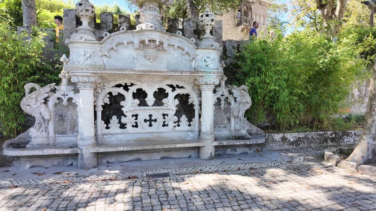 Gothic-style chapel surrounded by lush greenery with visitors exploring in Sintra, Portugal