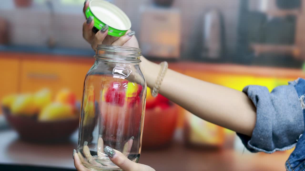 한 사람이 밝은 불빛으로 조명된 부에서 유리 항아리를 열고, 명확한 초점과 활기찬 색으로 간단하고 일상적인 행동을 보여줍니다.