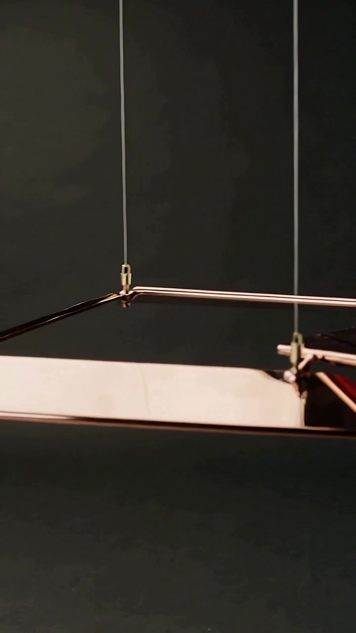 Vertical video: Rocking rose-gold frame panels after gentle push in studio, with brass connectors